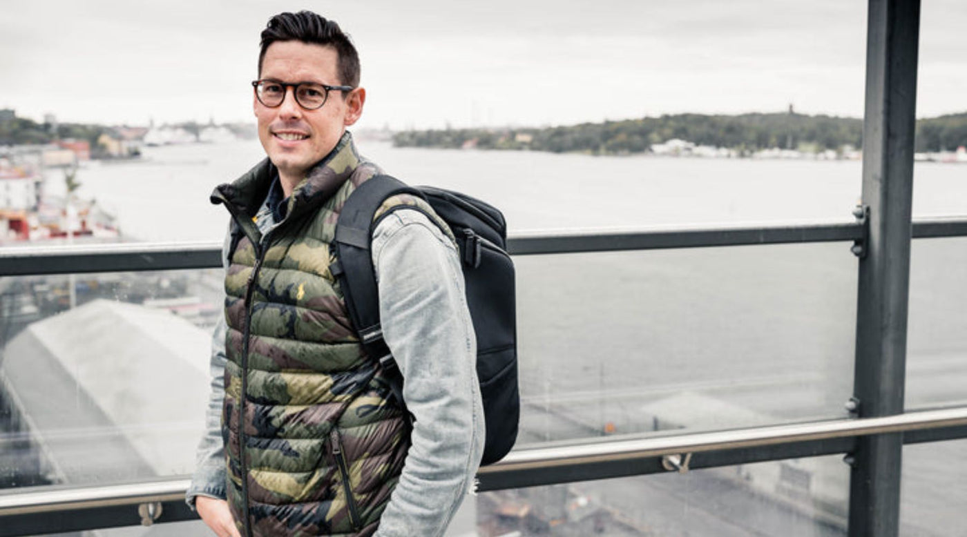 Mann-steht-auf-einer-Brucke-mit-einem-schwarzen-Rucksack