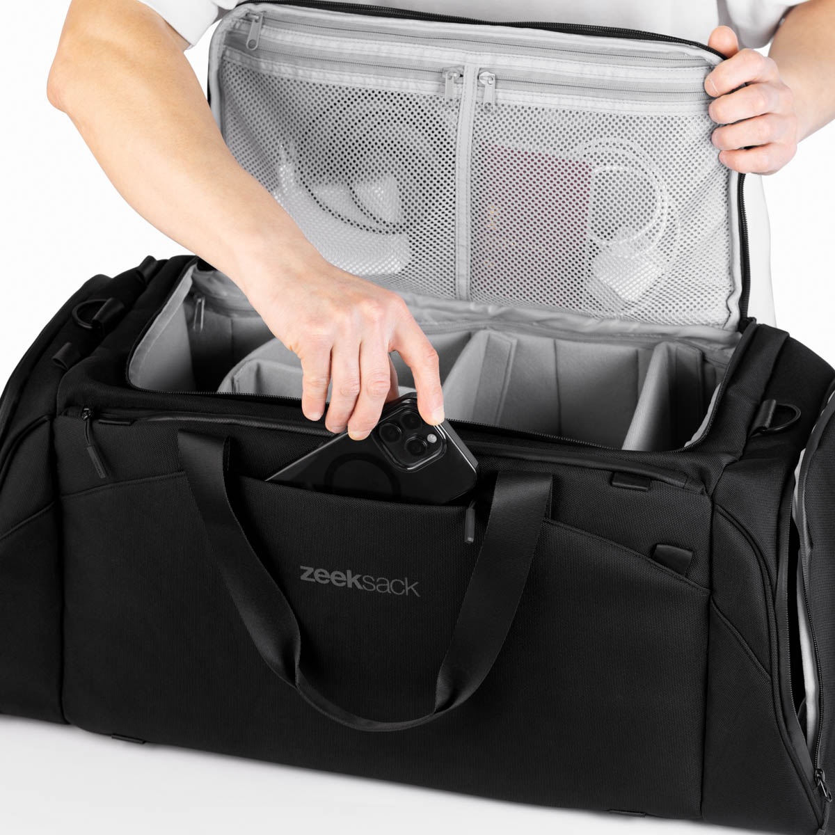 Ein Mann steckt ein Smartphone in das Außenfach einer schwarzen Zeeksack Duffelbag.