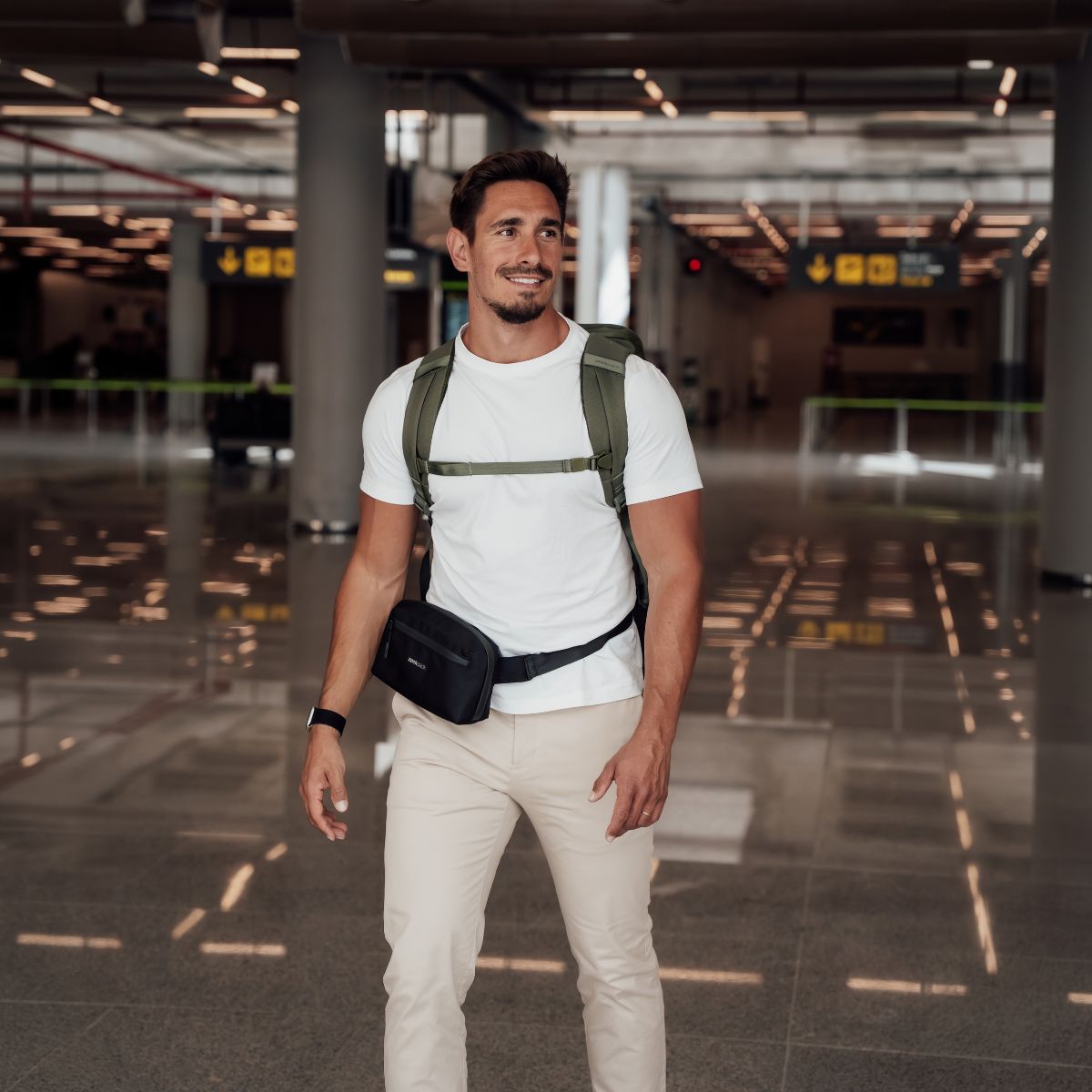 Zeeksack - Mann mit The Underseat 15L auf dem Rücken und Crossbody Organizer um die Hüfte am Flughafen.