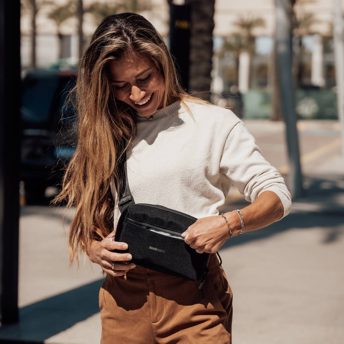 Eine Frau trägt den schwarzen Zeeksack Crossbody Organizer auf einer Straße.