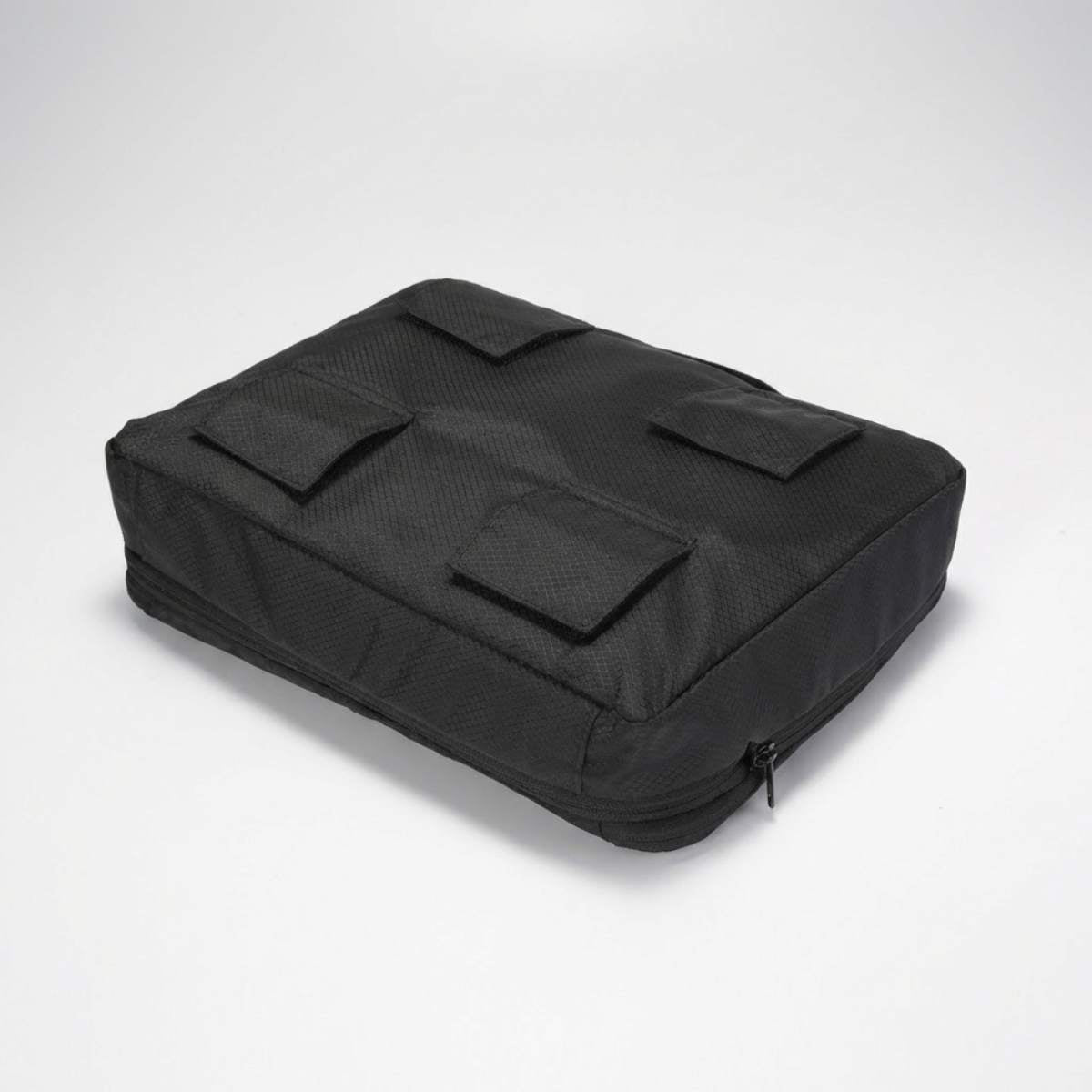 Schwarzer Packwürfel von unten mit vier Klettverschlüssen auf der Unterseite.