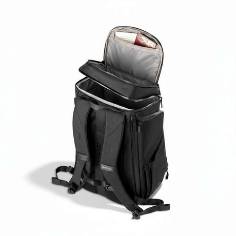 Schwarzer Rucksack von der Seite, steht auf dem Boden mit teilweise geöffnetem oberem Fach.