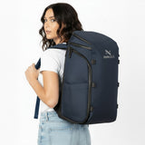 Frau mit marineblauem Rucksack auf dem Rücken.