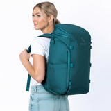 Frau mit petrolblauem Rucksack auf dem Rücken.