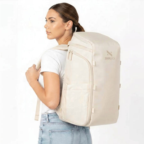 Frau mit sandfarbenem Rucksack auf dem Rücken.