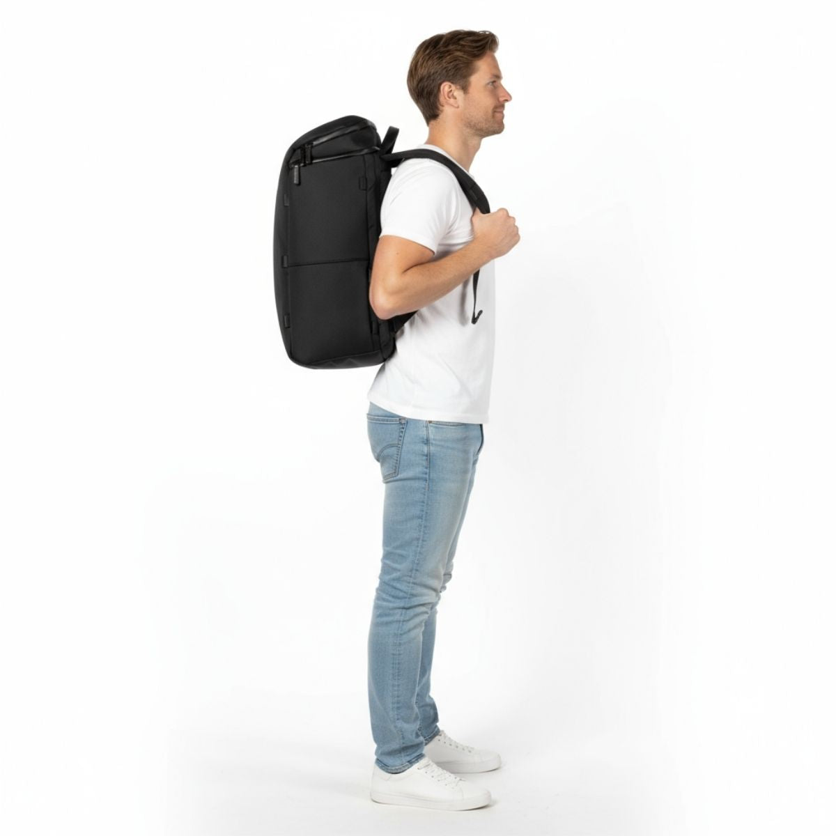 Mann im weißen T-Shirt und Jeans mit schwarzem Zeeksack-Rucksack, von der Seite gesehen.