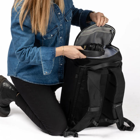 Frau legt Kopfhörer in das obere Fach des Zeeksack Organizer Rucksacks mit Netzinnentaschen
