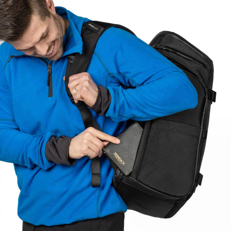 Mann zeigt auf die versteckte Sicherheitstasche am Rücken des Zeeksack Organizer, in der ein Reisepass steckt