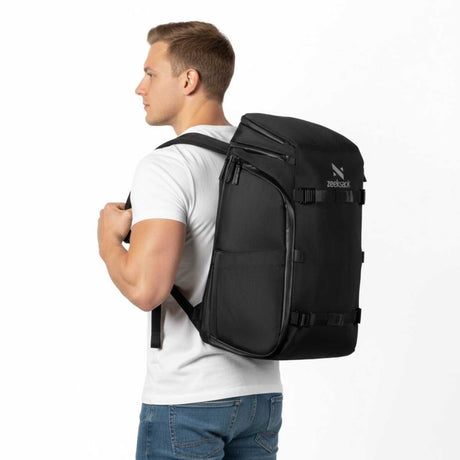 Mann trägt einen schwarzen Zeeksack Rucksack in seitlicher Ansicht mit sichtbarem Logo, robuster Rucksack für Arbeit, Alltag und Reisen.