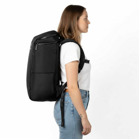 Frau trägt einen schwarzen Zeeksack Rucksack in seitlicher Ansicht, moderne Alltags- und Reiserucksack mit schlichtem Design.